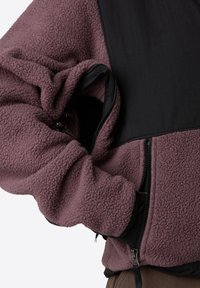 Giacca in pile di un profondo mauve con una parte superiore in nylon nero, dotata di zip frontale e polsini elastici. Tessuto testurizzato e caldo con tasche.