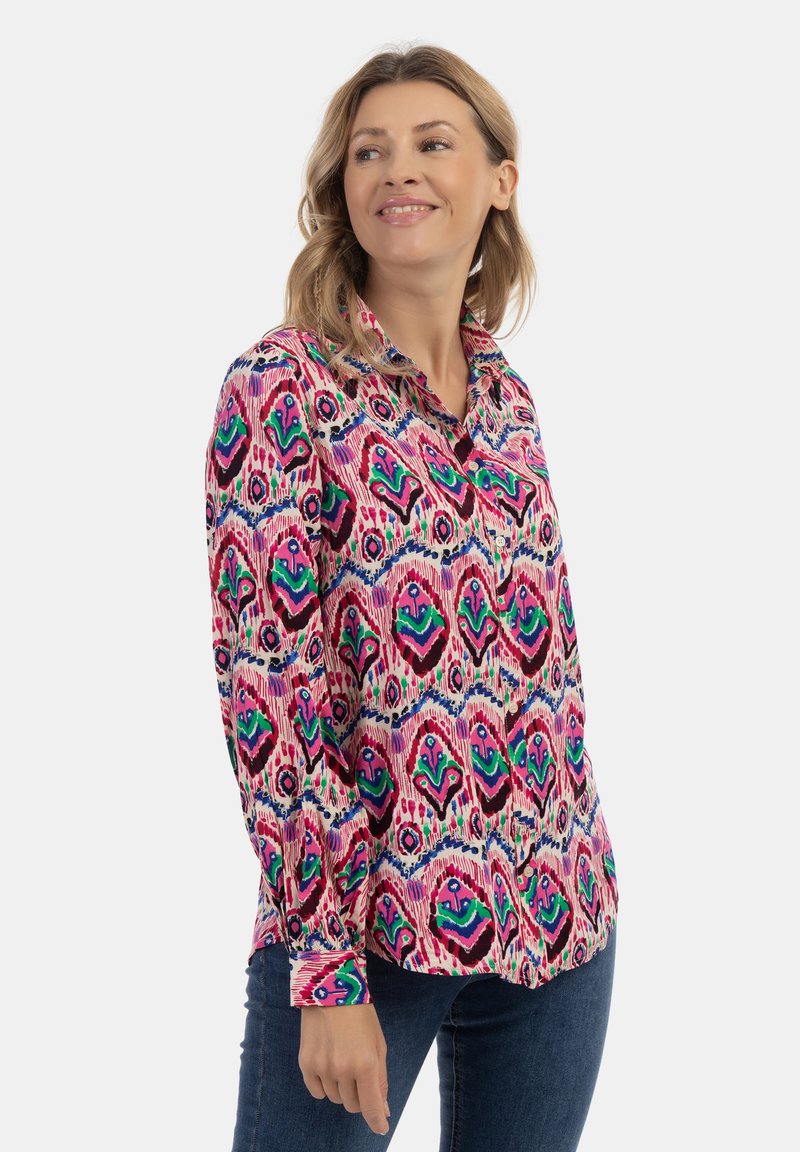 Camicia a maniche lunghe di colore rosa con motivo multicolore, realizzata in tessuto leggero con colletto a bottoni e maniche con polsino. Presenta elementi di design audaci.