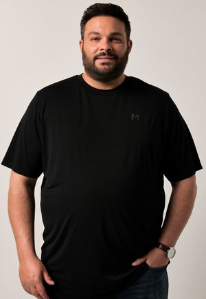 Camiseta negra de manga corta con cuello redondo, hecha de una tela suave y ligera. Presenta un pequeño logo en tono sobre tono en el pecho.
