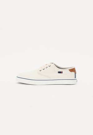 Bež canvas tüüpi sneaksid valge kummist tallaga, ümmarguse varbaga ning pruunist nahast aksendiga kanna juures. Omab tumesiniseid ja punaseid triibudetaile.