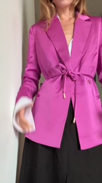 Blazer de cetim rosa brilhante com laço na cintura, mangas longas e punhos interiores brancos contrastantes. Apresenta dois bolsos laterais e um corte descontraído.