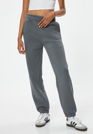 Grijze sweatpants van zachte stof, met een relaxte pasvorm, elastische tailleband en boorden, gecombineerd met witte sneakers.
