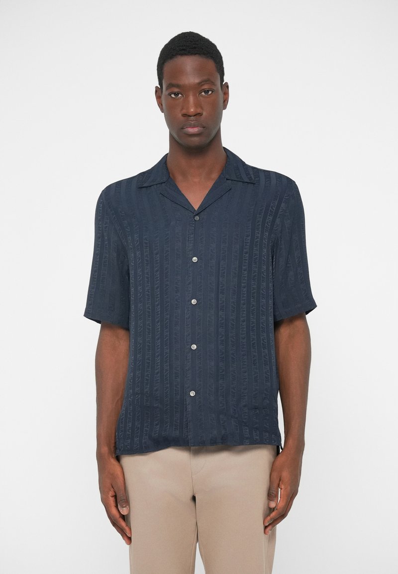 Kortärmad marinblå skjorta med knappar och vertikala ränder, tillverkad av lättviktig tyg. Har en camp-krage och en avslappnad passform.
