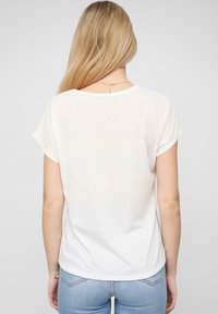 Hvid kortærmet t-shirt med en afslappet pasform og opfoldede ærmer. Blødt, let stof med en let gennemsigtig tekstur.