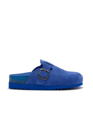 Niebieskie zamszowe klapki typu slip-on z szerokim regulowanym paskiem i srebrną klamrą, wyposażone w teksturowaną podeszwę i otwarty tył dla łatwego zakładania.