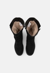 Bottes noires en daim montant jusqu'au genou avec une douce doublure en polaire beige, un design ample et des détails de couture à l'extérieur. Fermeture éclair placée près du haut.