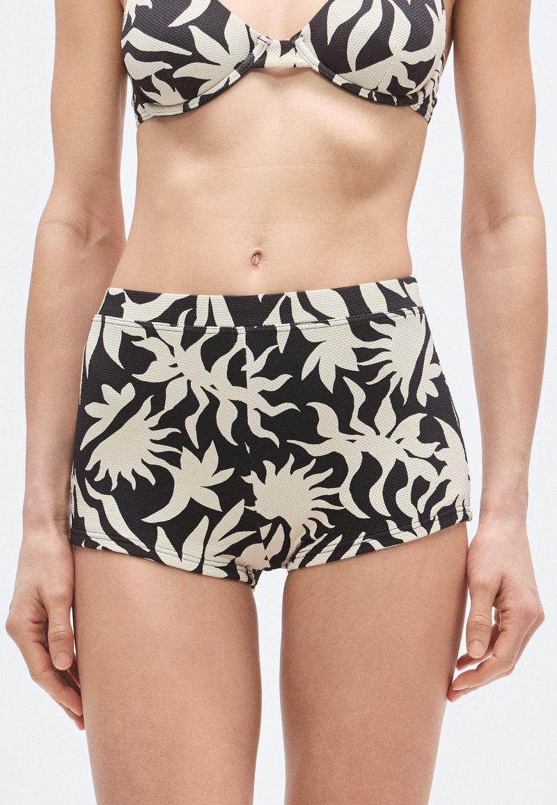 Calções de banho de cintura alta com tecido texturizado. Base preta com padrões de folhas bege. Apresenta um corte ajustado e cós largo.