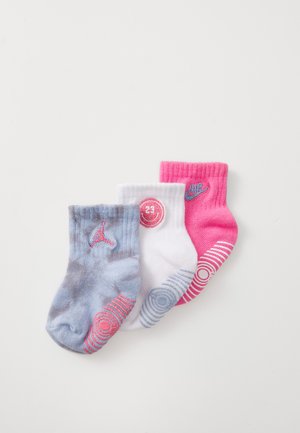 Tre par med barnens ankelstrømper: grå med rosa detaljer, hvite med et sirkulært logo, og rosa med blå logo og stripemønster.