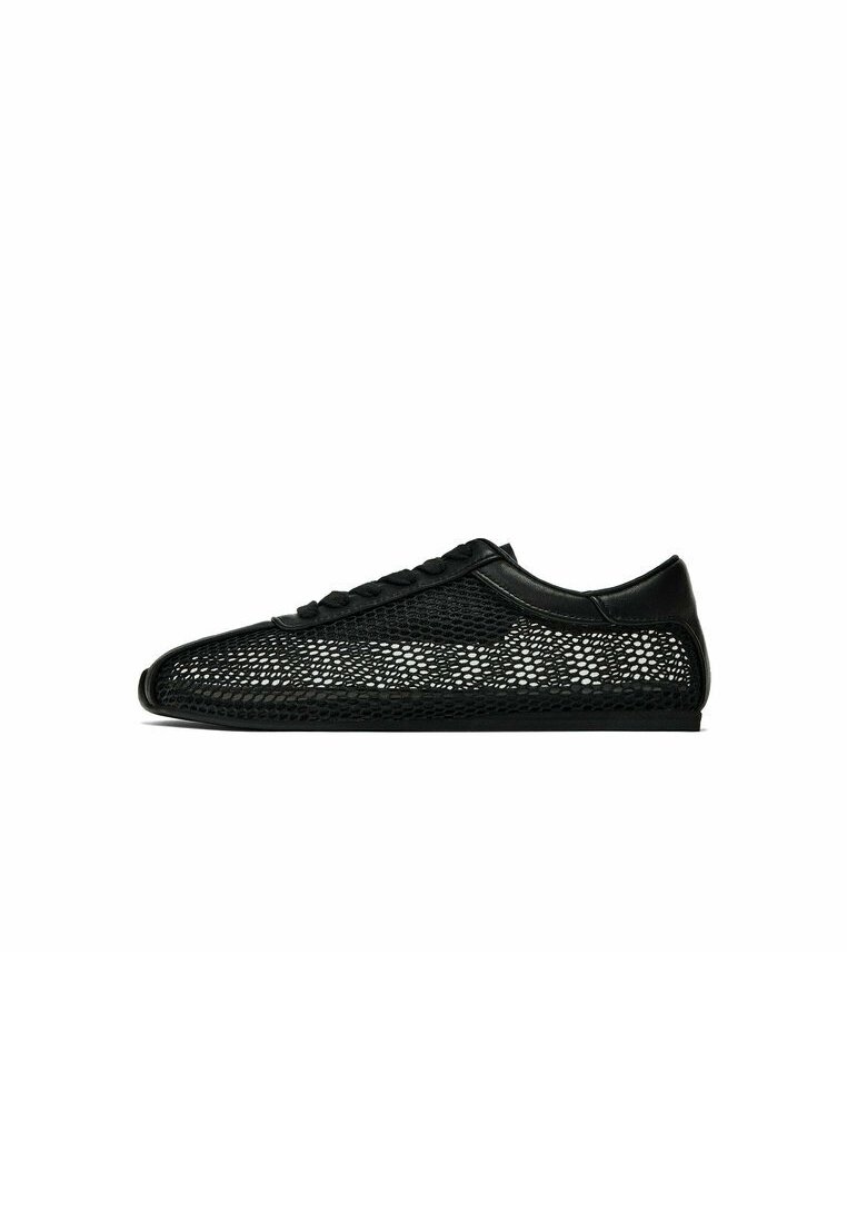 Baskets basses noires avec un design en maille et embout, talon et lacets noirs unis sur fond blanc.