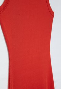 Robe rouge sans manches en tissu côtelé, vue de profil sur un fond clair.