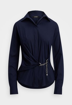 Marineblauwe blouse van gladde stof, voorzien van een puntkraag, lange mouwen en een gedraaide voorkant met een zilveren kettingaccent.