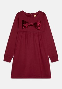 Burgundy långärmad klänning med en mjuk textur, med en sammetsdetalj i form av en rosett på framsidan och en insydd midja för en avslappnad passform.