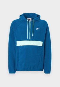 Zilā flīsa kapuce ar gaiši zilu paneli un kabatu. Iespējo kanguru kabatu un balto Nike logotipu uz krūtīm.