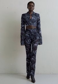 Μαύρο και γκρι μοτίβο σε σετ ένδυσης δύο τμημάτων που περιλαμβάνει ένα κοντό μακρύ μανίκι τοπ με άνοιγμα και εφαρμοστά παντελόνια με μακριά μανίκια.