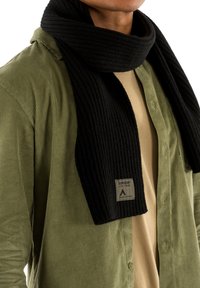 Sort ribbet tørklæde lavet af blødt stof, draperet om halsen. Det har et logo mærke med "Superdry" på en lap.