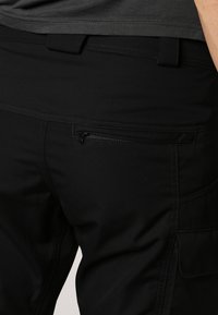 Pantalons cargo noirs en tissu lisse, dotés de plusieurs poches, d'une poche arrière zippée et de coutures contrastées le long des coutures.