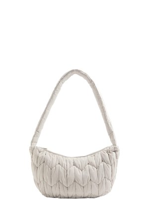 Quilted handbag in light beige, featuring a curved silhouette, soft material, and a padded strap for comfort. Zipper closure at top.