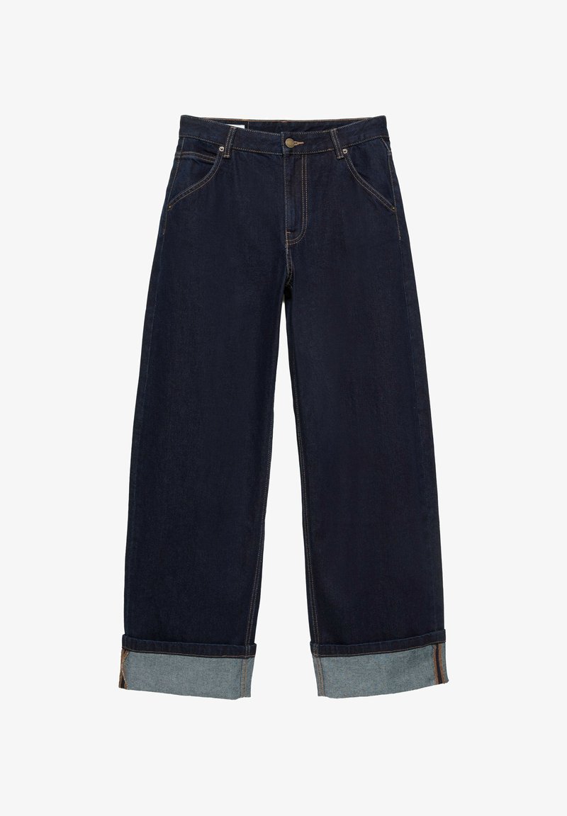 Jean en denim bleu foncé avec ourlets retournés, bouton et fermeture éclair à l'avant, poches devant et détails de coutures visibles.