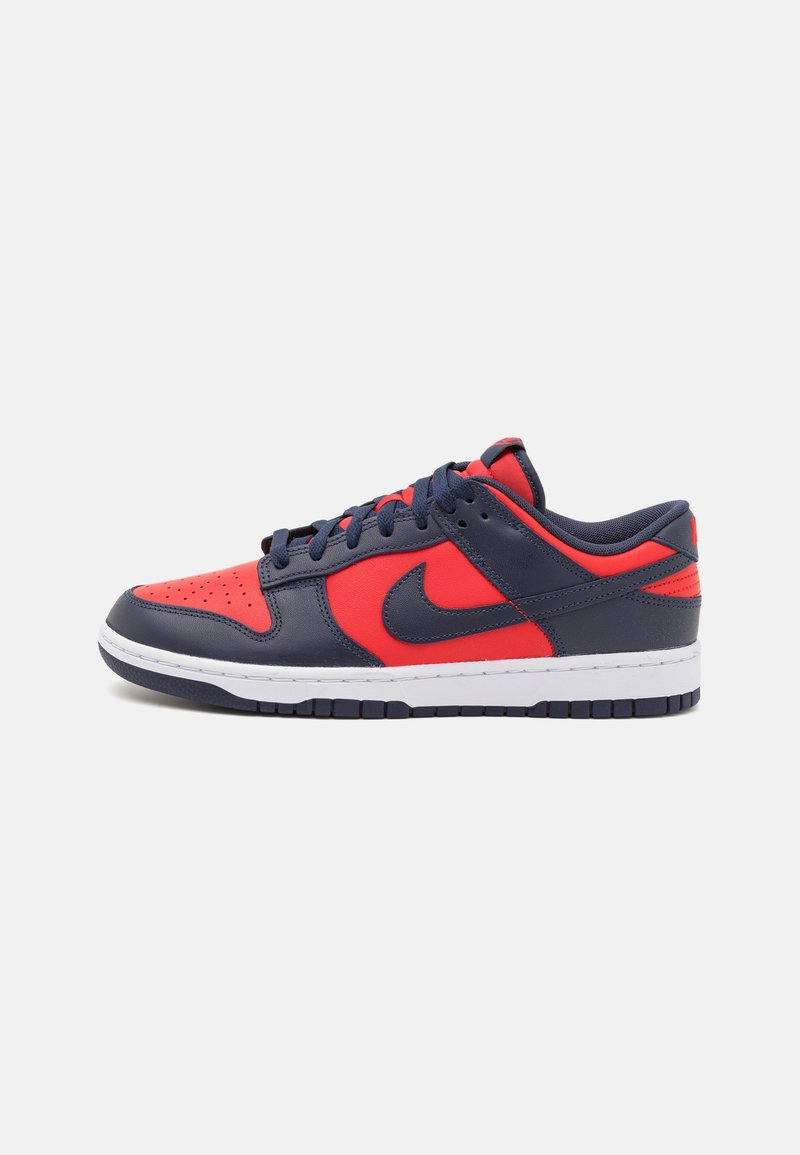 Baskets basses Nike en cuir bleu foncé et rouge vif avec lacets noirs et semelle blanche, vues de côté sur fond blanc.