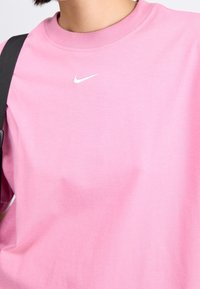 Rosa Nike sweatshirt med rund halsringning, tillverkad av en mjuk bomullsblandning. Har en liten vit Nike-logotyp på bröstet och en avslappnad passform.