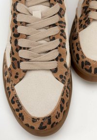 Sneaker in suede tan con dettagli leopardati, lacci piatti beige e suola in gomma texturizzata. Presenta un design a punta rotonda e liscia.