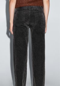 Zwarte corduroybroek met een rechte pasvorm, voorzien van verticale ribbels, twee achterzakken en een middelhoge tailleband.