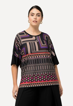 La blusa de manga corta presenta un patrón geométrico multicolor en tonos de púrpura, negro y rosa, con un dobladillo sólido negro y detalles en negro.