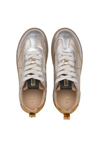 Metallisch silberne und beige Sneakers aus strukturiertem Leder, weiße Schnürsenkel und ein schwarzes Etikett mit goldenen Streifen. Goldene Akzente an der Ferse.