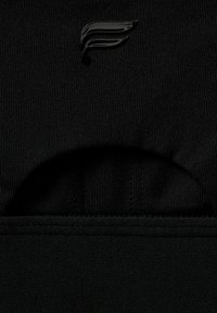 Schwarzes, tailliertes Sportoberteil mit einer eleganten, gerippten Textur und einem glänzenden Logoakzent. Minimalistisches Design ohne zusätzliche Verzierungen.