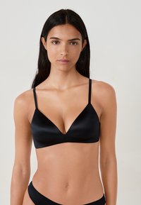 Soutien-gorge en satin noir avec un décolleté en V plongeant, de fines bretelles réglables et des bonnets sans couture, conçu pour un ajustement lisse.