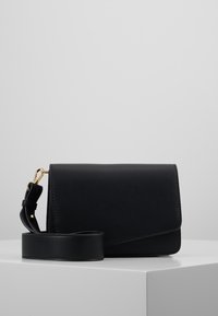 Borsa a tracolla in pelle nera con chiusura a patta, dettagli in metallo dorato e tracolla removibile, caratterizzata da una texture liscia e un design minimalista.