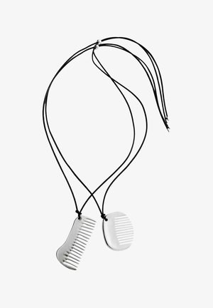 Deux pendentifs argentés en forme de peigne sur cordons noirs, chacun avec des motifs de dents distincts, présentés sur fond blanc.