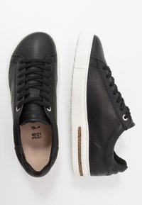 Baskets en cuir noir avec une surface texturée, semelle en caoutchouc blanche, design à lacets et détail en liège sur la semelle intermédiaire. Taille indiquée à l'intérieur.