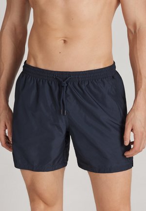 Marineblaue Badeshorts mit elastischem Bund und verstellbarem Kordelzug. Hergestellt aus leichtem Material, das eine glatte Textur und ein minimalistisches Design aufweist.