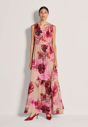 Maxikleid mit floralen Mustern in Beige und pinkfarbenen tropischen Blättern, mit ärmellosem Design, V-Ausschnitt und gestuftem Rock, kombiniert mit roten High Heels.