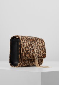Leopardikuvioinen käsilaukku, jossa mustat nahkaosat, kultaiset metalliosat ja hapsukoriste. Kompakti muotoilu, jossa läppäkiinnitys.