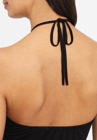 Schwarzes Halsband-Top mit dünnen Bändern am Hals. Glatter Stoff mit einer figurbetonten Passform, der den Rücken mit einer geschwungenen Nahtdetails freilegt.