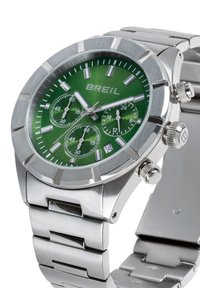 Montre chronographe en acier inoxydable argenté avec cadran vert, trois sous-cadrans, trois poussoirs et un bracelet à maillons polis.