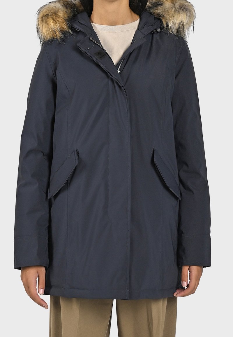 Námořnická parka s kapucí podšitou umělou kožešinou, dvěma předními kapsami a zipovým uzávěrem. Vyrobena z hladké, povětrnostně odolné látky.