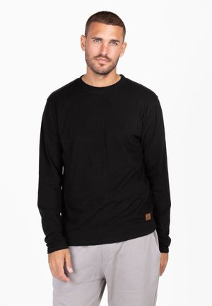 T-shirt nero a maniche lunghe in un tessuto morbido con scollatura rotonda, caratterizzato da un piccolo etichetta marrone sul lato sinistro inferiore. Vestibilità casual.