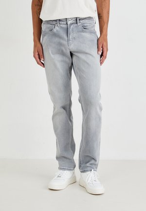 Lichtgrijze denimjeans met een relaxte pasvorm, voorzien van voorzakken, een knoopsluiting en subtiele vervaging. Gepaard met witte sneakers.