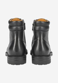 Bottes chevilles en cuir noir à finition lisse avec semelles en caoutchouc robustes. Elles sont dotées d'une fermeture éclair arrière et d'un col rembourré pour plus de confort.