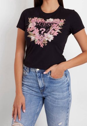 Czarna bawełniana koszulka z kwiatowym różowym i zielonym nadrukiem przedstawiającym wzór w trójkąt oraz napisem "GUESS U.S.A.", połączona z jasnoniebieskimi dżinsami.