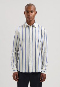 Gestreiftes Langarmhemd in Hellbeige und Blau, mit durchgehender Knopfleiste, klassischem Kragen und texturiertem Stoff mit vertikalen Streifen.