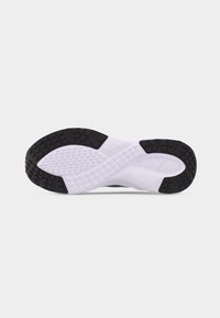 Εξώφτερνου μέρος αθλητικού παπουτσιού με μαύρη και λευκή ελαστική σόλα και υφή με σχέδια πρόσφυσης, με μικρό λογότυπο Puma κοντά στη φτέρνα.