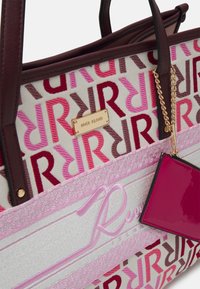 Canvas tote bag med bruna läderhandtag, med ett upprepande logotypmönster i rosa och vinröd. Inkluderar en avtagbar rosa kortficka.
