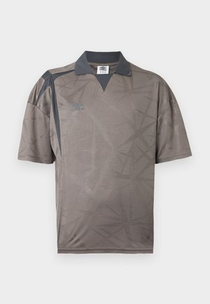 Κοντομάνικη γκρι αθλητική φανέλα με σκούρο γιακά και πάνελ στους ώμους, διακριτικό γεωμετρικό μοτίβο και λογότυπο Umbro στο στήθος.