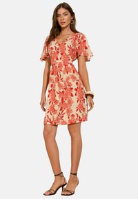Rochie florală cu decolteu în V, cu mâneci scurte și evazate, având un model floral roșu-portocaliu pe un fundal bej deschis.