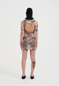 Vestido corto ajustado en tela texturizada y colorida, con un corte en la espalda, patrones detallados y un cierre de lazo en la cintura.