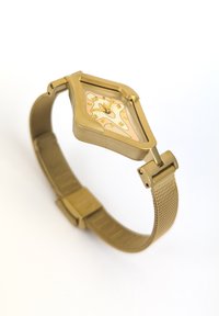 Guldlegering ur med et unikt sekskantet urskive, der har et hvidt og ferskenfarvet design. Netarmbånd og guldfarvet hardware til lukning.